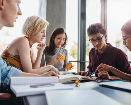 A group of students collaboratively work at a desk.