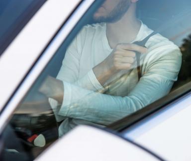 A bearded man fastening a seatbelt.