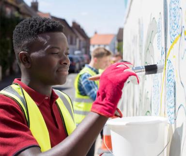 A young man paints a mural
